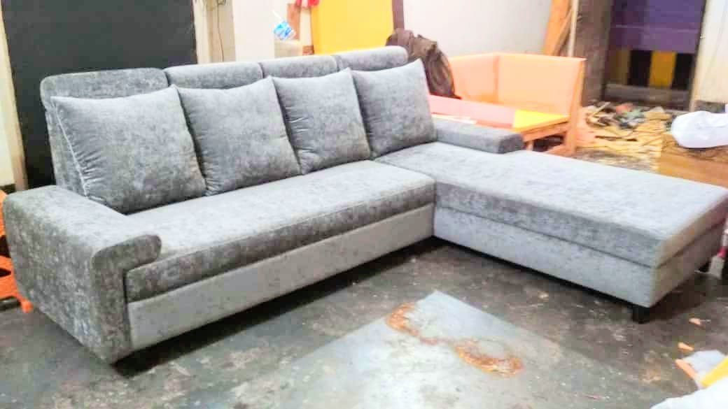 Light grey textured fabric L-sectional sofa with scatter cushions in workshop